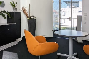 Blick in das moderne private Büro mit orangenen Design-Stühlen und rundem Tisch im Coworking Space CoWirken Schorndorf