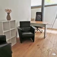 Komplett eingerichtetes Büro im Fokus-Bereich von CoWirken Schorndorf mit Schreibtisch, Flipchart, zwei bequemen Ledersesseln und Echtholzparkett.