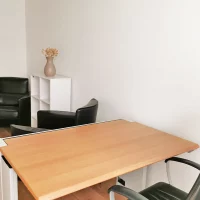 Perspektive auf den Arbeitsplatz im Private Office Fokus bei CoWirken Schorndorf mit Schreibtisch aus Holz und einer zusätzlichen Besprechungsecke im Hintergrund.
